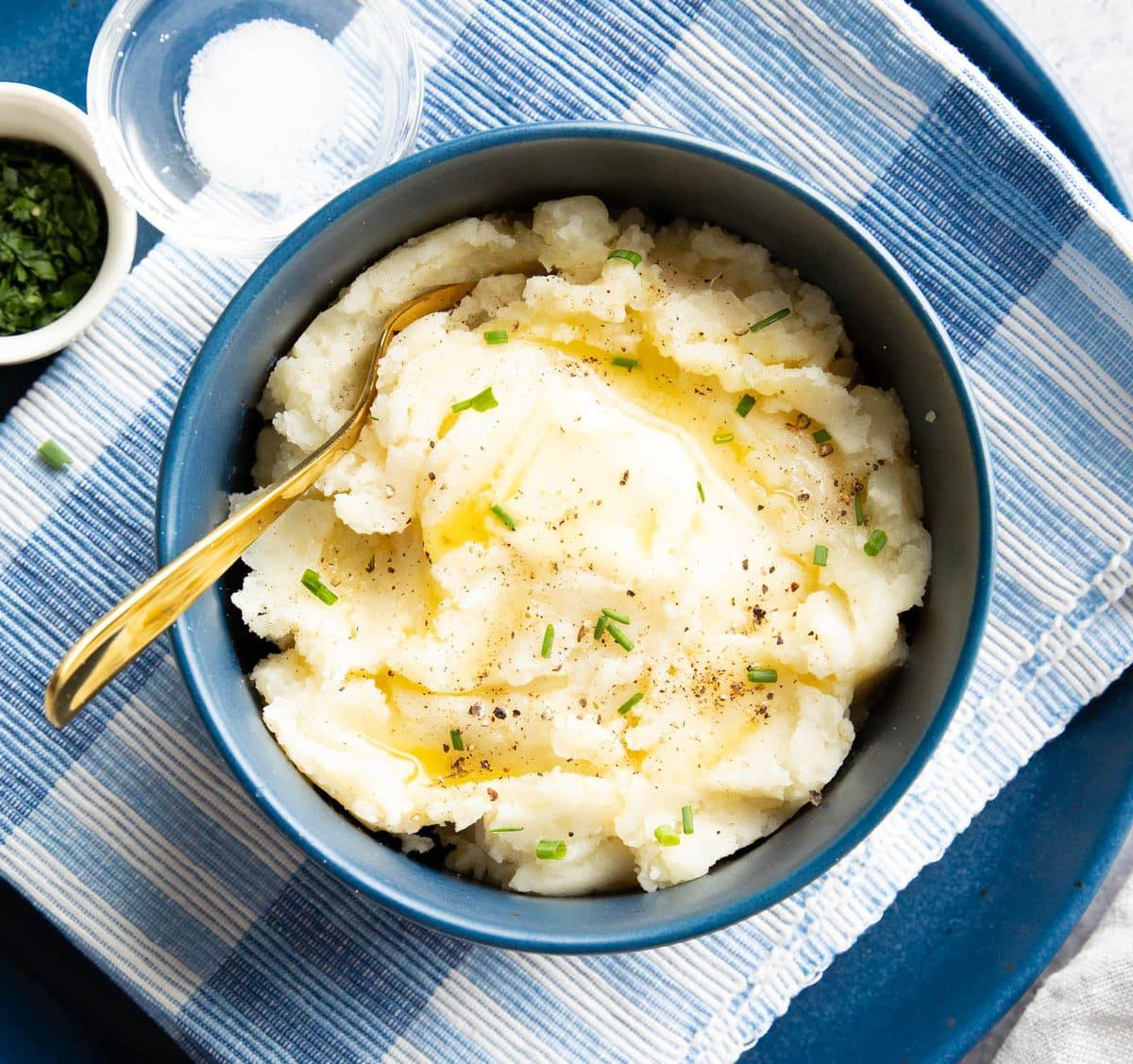 Veganes Kartoffelpüree in einer Schüssel, garniert mit veganer Butter und Schnittlauch