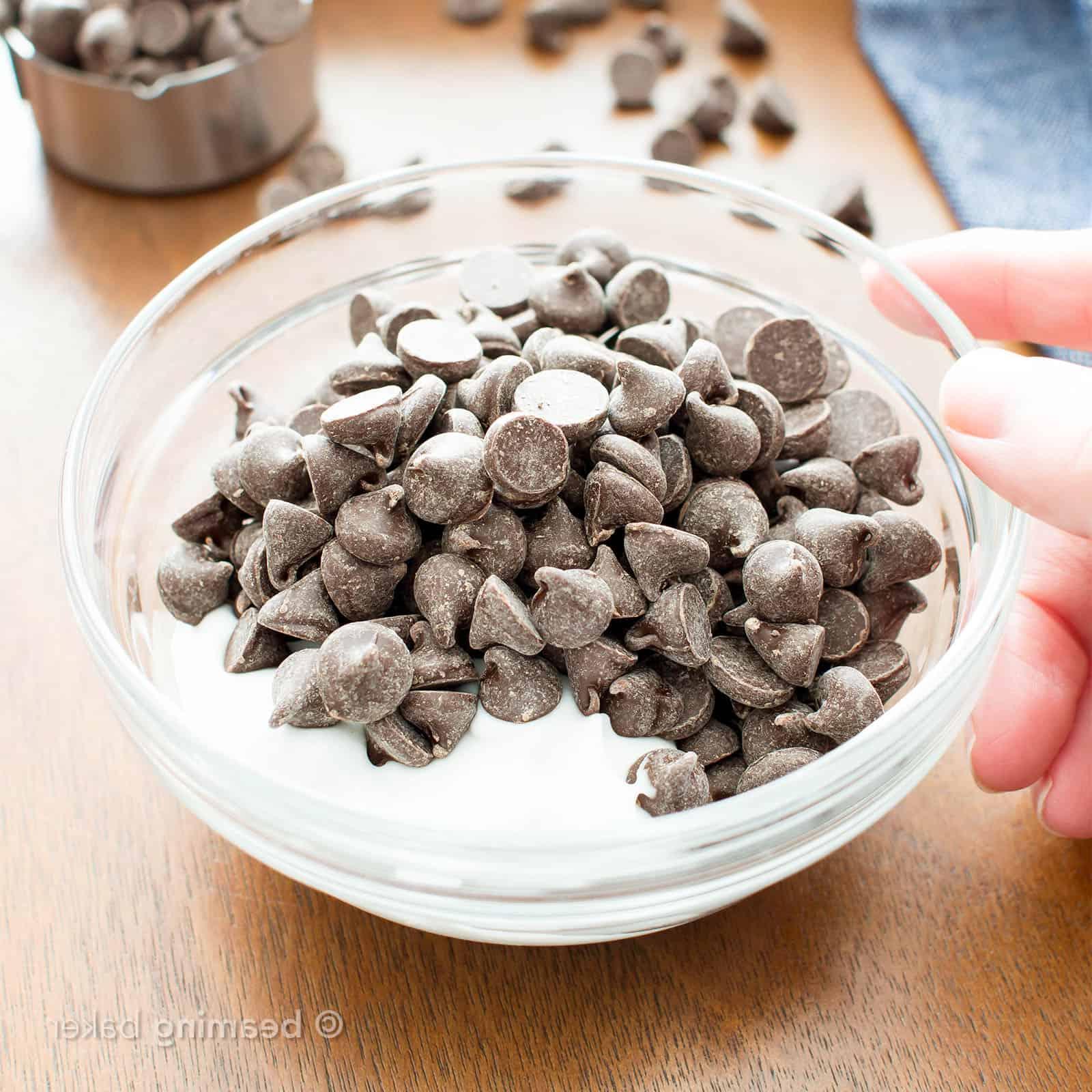 Vegane Schokoladen-Ganache: Vegane Schokoladenchips und Kokoscreme in einer mikrowellengeeigneten Schüssel zum Schmelzen vorbereitet.