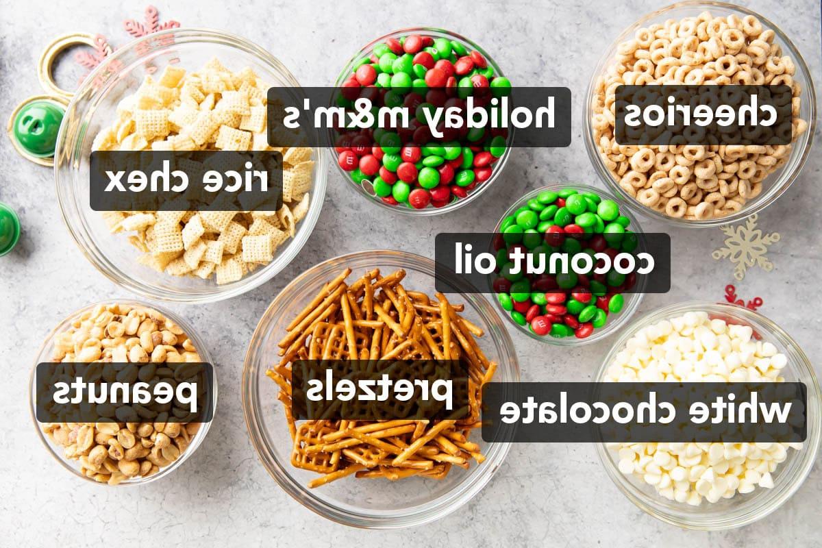 Schüsseln mit Brezeln, Reis-Chex, Cheerios, Erdnüssen, roten und grünen Weihnachts-M&M-Bonbons und weißen Schokoladenstückchen zur Herstellung von Weihnachtlichem Rentierfutter