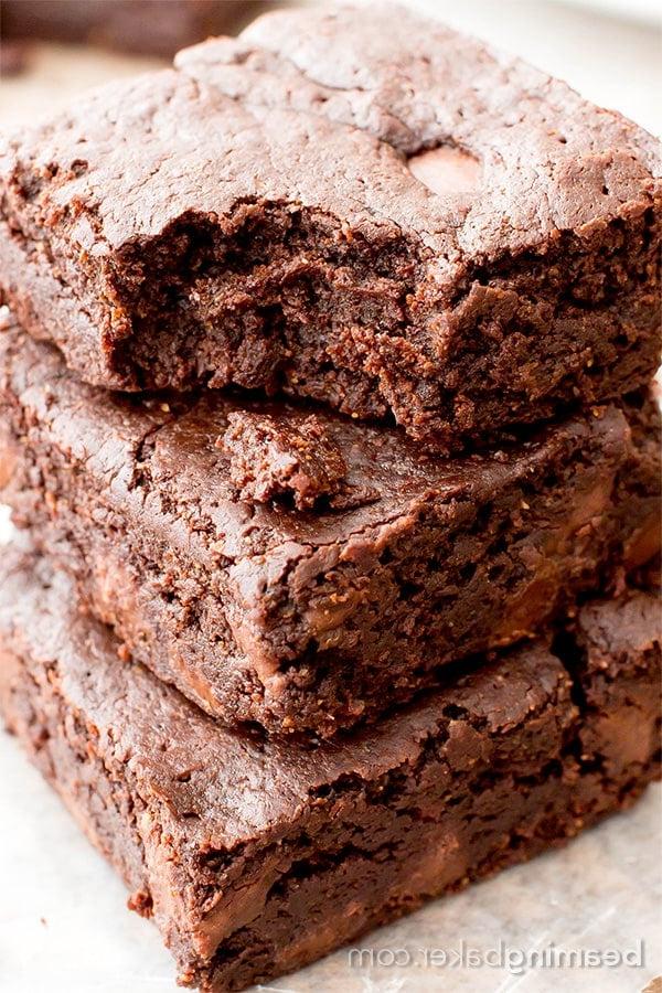 Ein angebissener veganer GF-Brownie liegt auf zwei weiteren Brownies auf Wachspapier
