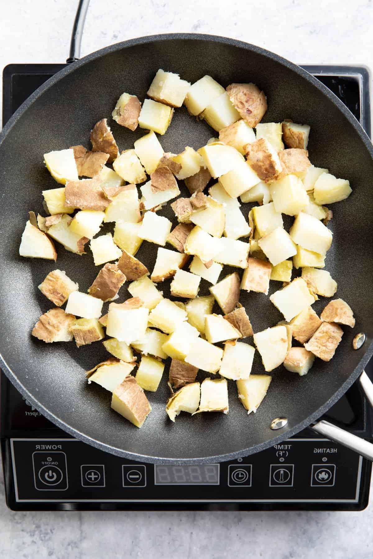 Gehackte Kartoffeln kochen in einer antihaftbeschichteten Pfanne über der Hitze