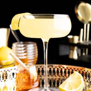 Ein Bee's Knees Cocktail in einem Glas mit Zitronengarnitur