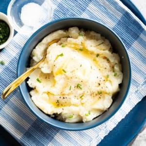 Schüssel mit veganem Kartoffelpüree, garniert mit geschmolzener veganer Butter und grünem Schnittlauch