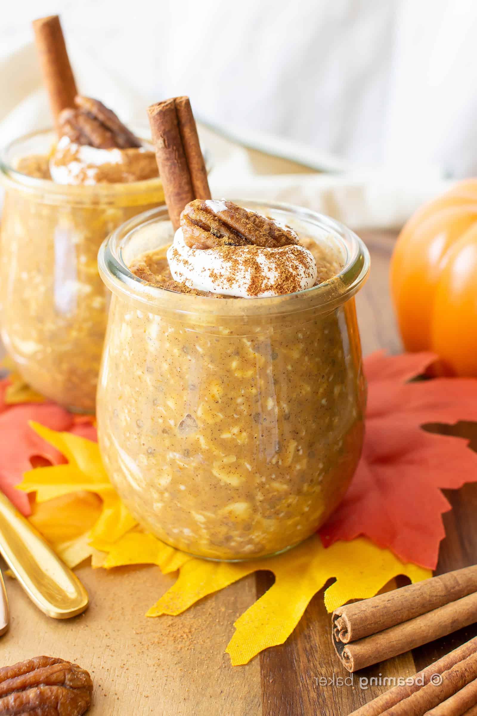 Kürbis-Overnight-Oats 3 Gläser mit Kürbis Overnight Oats mit Schlagsahne und einer Zimtstange