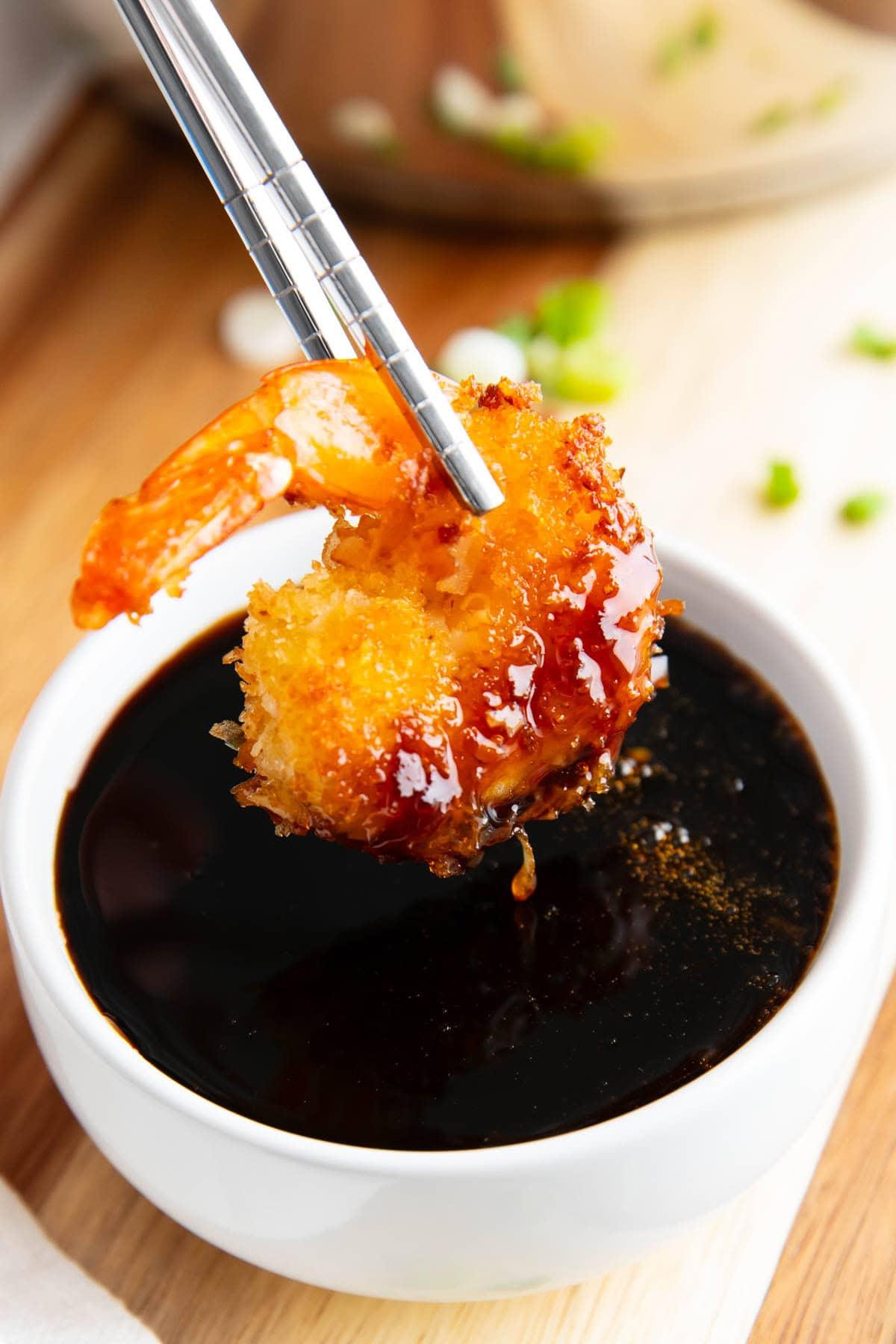 Essstäbchen halten eine in dieses Aalsoßenrezept getauchte Tempura-Garnele.